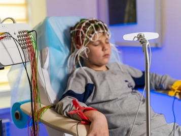 Boy Sitting in Medical Chair Wearing Special Cap During Electroencephalography Monitoring