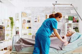 Nurse Assisting Elderly Woman to Bed, Covering Her with a Blanket in a Nursing Retirement Home