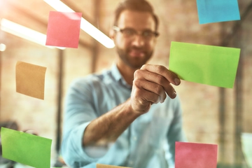 Kanban Board with a Young Man Using Colorful Stickers